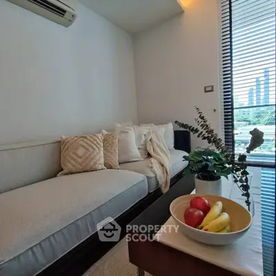 Stylish living room with cozy sofa, modern decor, and city view through large window blinds.