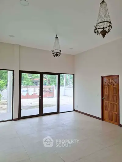 Spacious living room with large windows and elegant chandeliers, offering a bright and airy atmosphere.