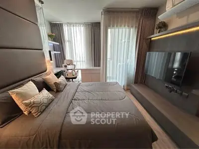 Modern bedroom with stylish decor and wall-mounted TV, featuring large windows and elegant curtains.