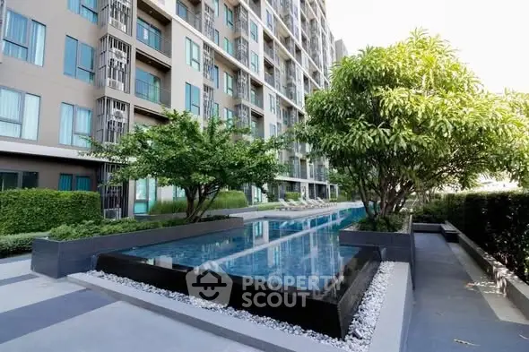 Modern condominium with sleek pool and lush greenery in urban setting.