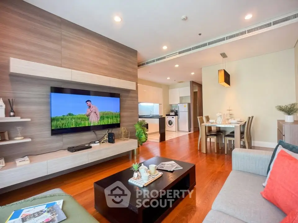 Spacious modern living room with open kitchen and dining area, featuring stylish decor and hardwood floors.