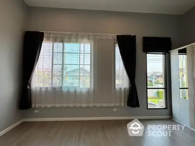 Spacious empty room with large windows and elegant curtains, perfect for customization.