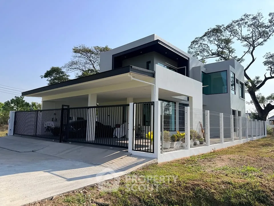 Modern two-story house with sleek design and spacious driveway, surrounded by greenery and clear blue sky.