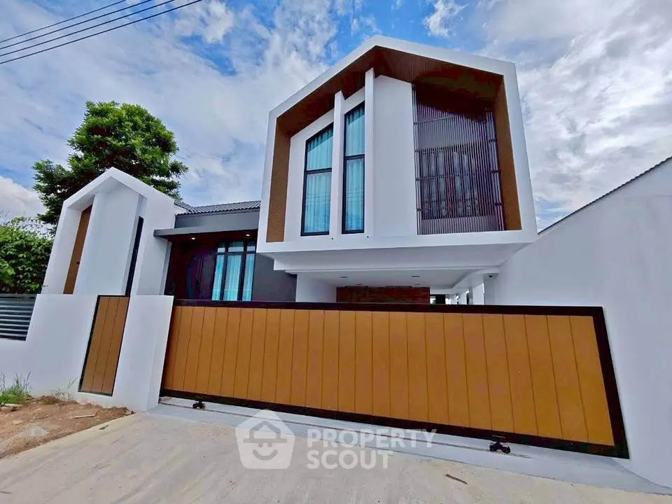 Modern two-story house with sleek design and large windows, featuring a stylish wooden gate and contemporary architecture.
