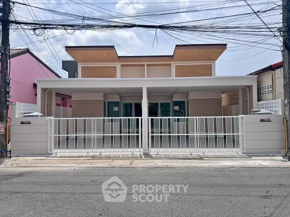 Modern single-story house with sleek design and gated entrance on a quiet street.