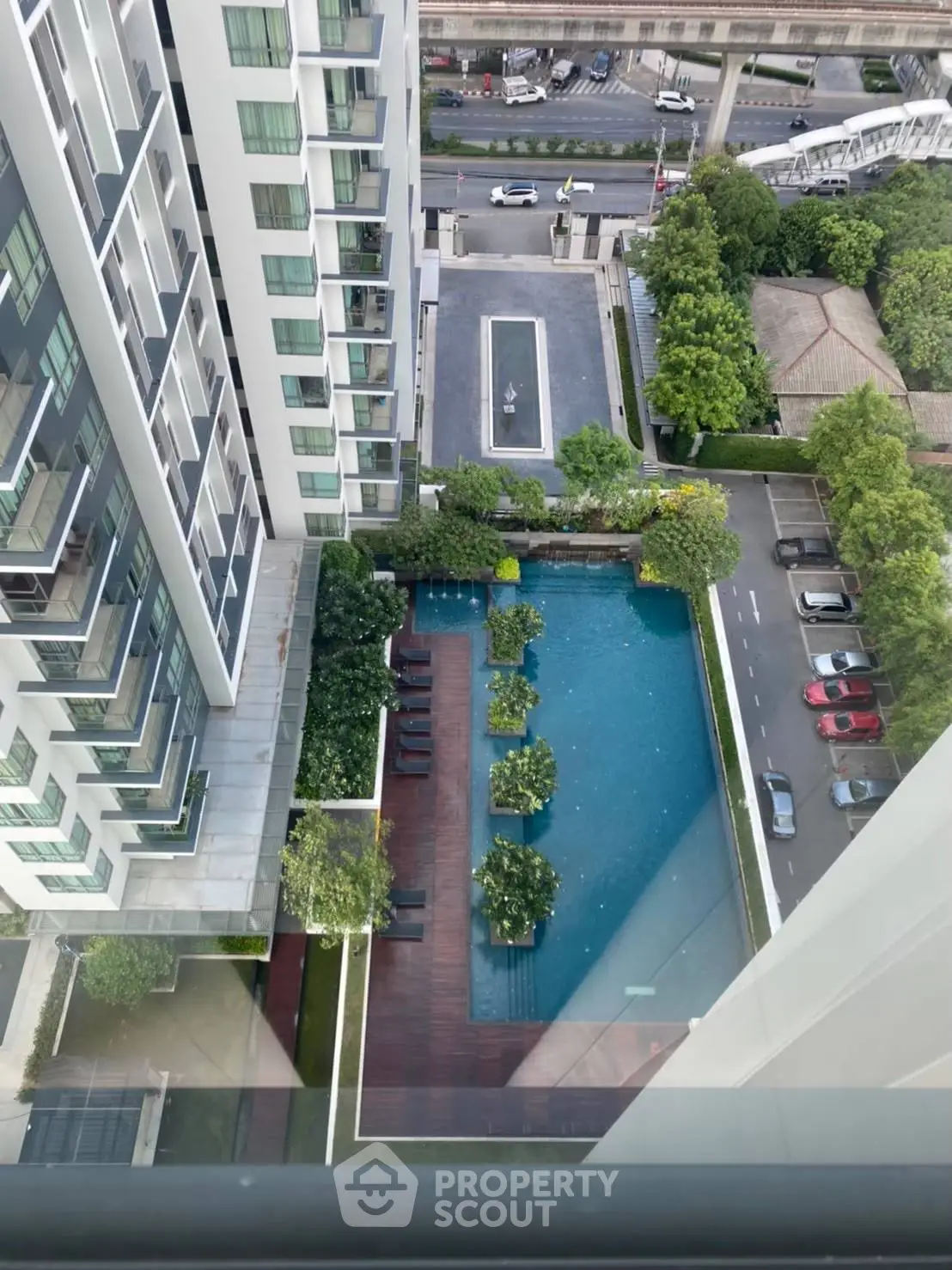 Stunning aerial view of modern condominium with luxurious pool and lush greenery, perfect urban living.