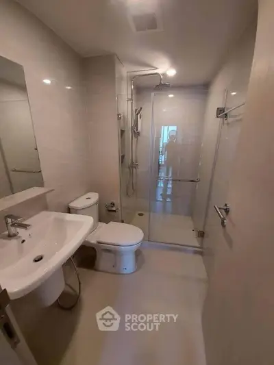 Modern bathroom with glass shower enclosure and sleek fixtures in a contemporary apartment.