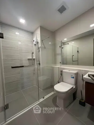 Modern bathroom with glass shower and sleek fixtures in contemporary home.
