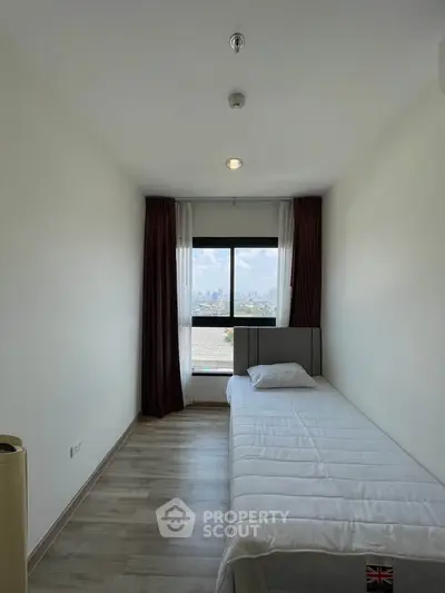 Cozy bedroom with single bed and city view, perfect for urban living.
