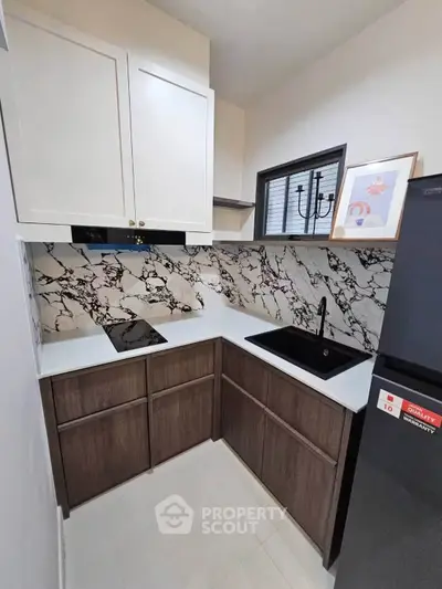 Modern kitchen with sleek design, marble backsplash, and black sink, perfect for culinary enthusiasts.