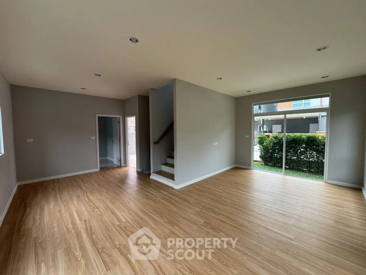 Spacious modern living room with wooden flooring and garden view.