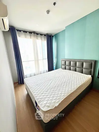 Spacious bedroom with large window and modern decor in a high-rise apartment.