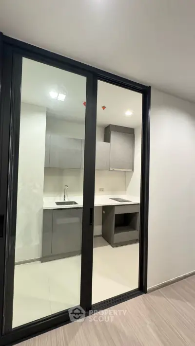 Modern kitchen with sleek cabinetry and sliding glass doors in a contemporary apartment.