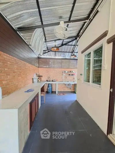 Spacious outdoor kitchen with brick wall and modern appliances, perfect for entertaining guests.