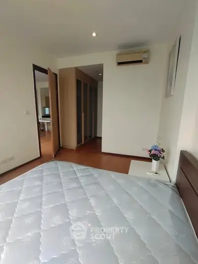 Spacious bedroom with air conditioning and wooden flooring in modern apartment