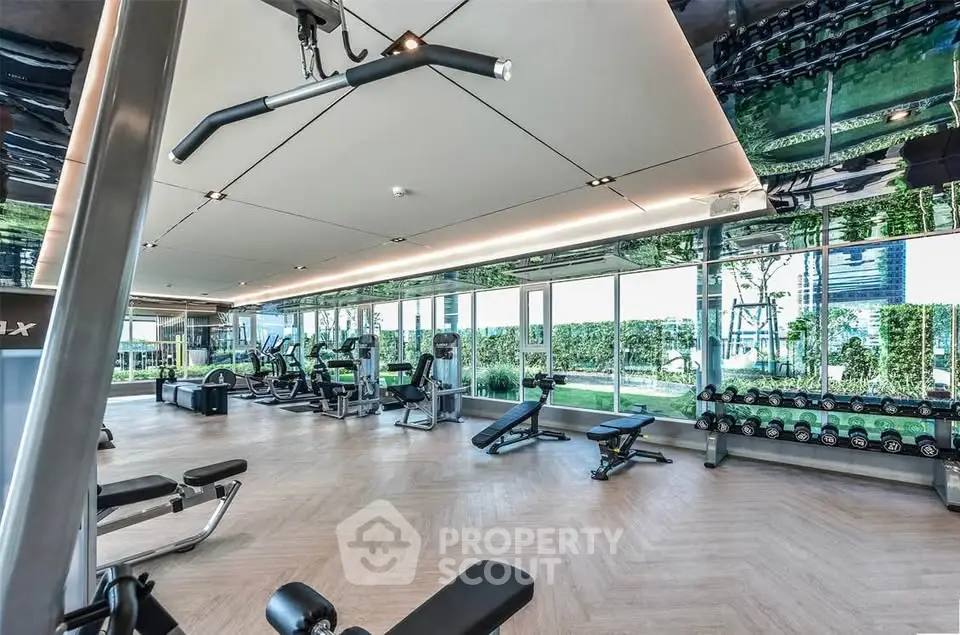 Luxurious gym with modern equipment and floor-to-ceiling windows offering garden views.