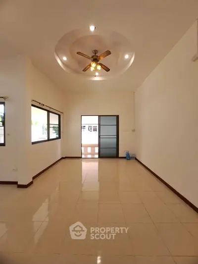 Spacious living room with ceiling fan and large windows in modern home.