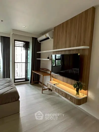 Modern bedroom with stylish wooden paneling and wall-mounted TV, featuring a cozy bed and natural light.