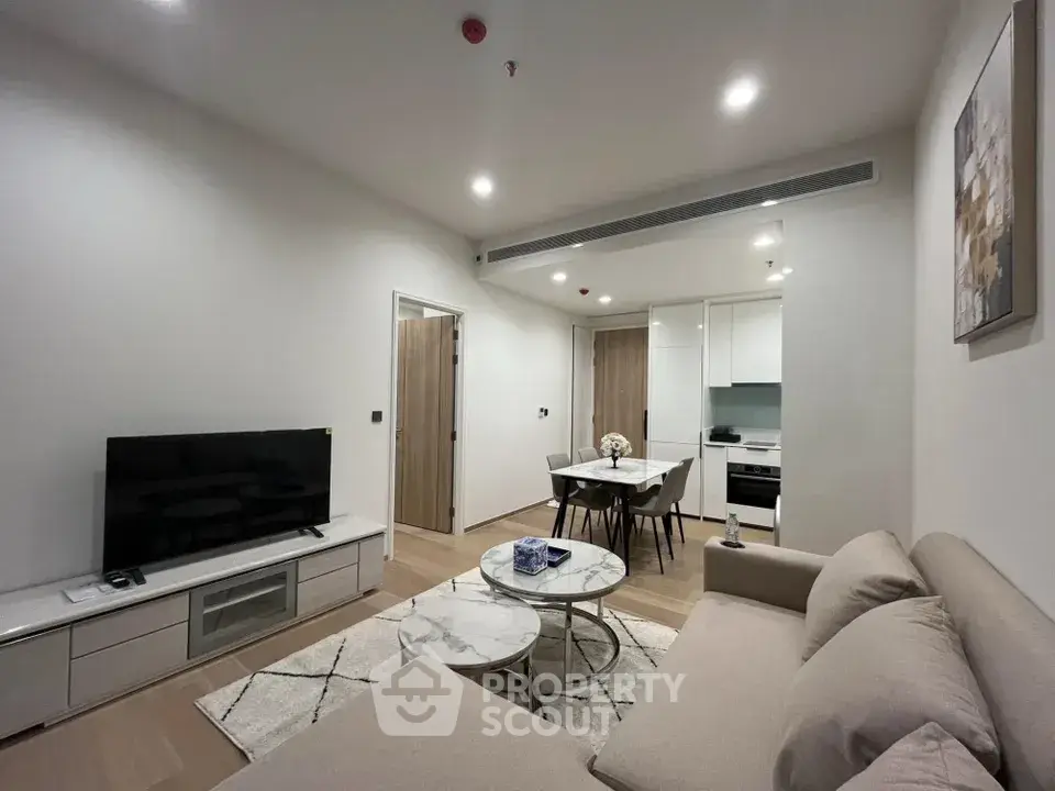 Modern living room with cozy sofa, TV, and open kitchen layout in stylish apartment.