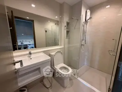 Modern bathroom with sleek fixtures and glass shower enclosure in a contemporary apartment.