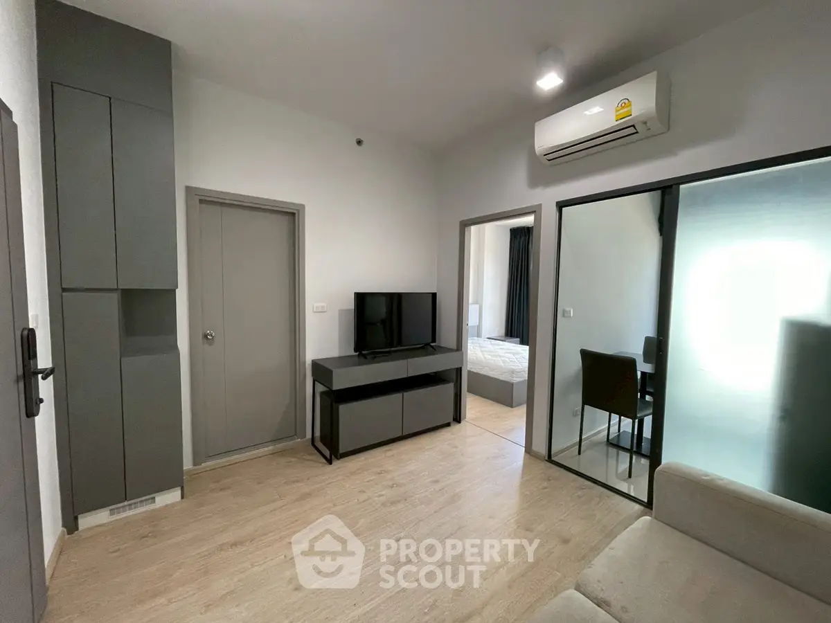 Modern living room with sleek design, featuring air conditioning and a view into the bedroom.