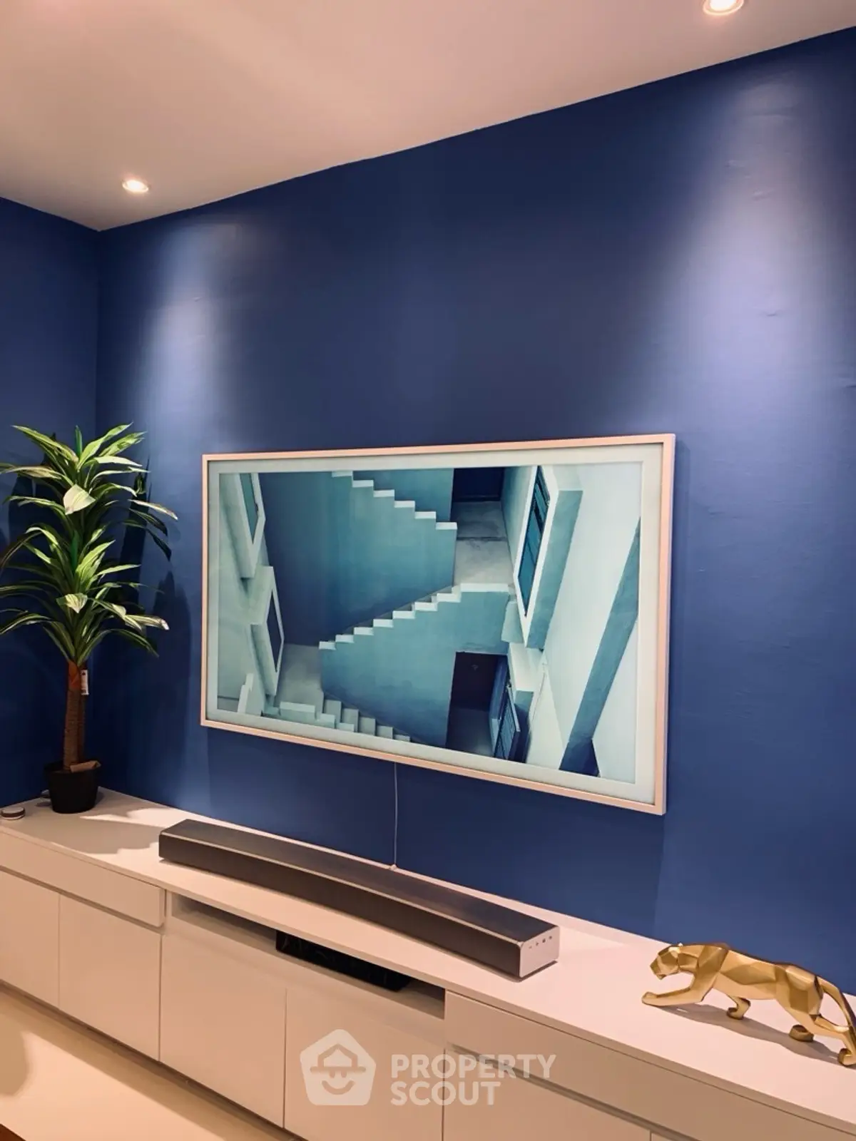 Modern living room with blue accent wall, stylish TV setup, and sleek white cabinetry.