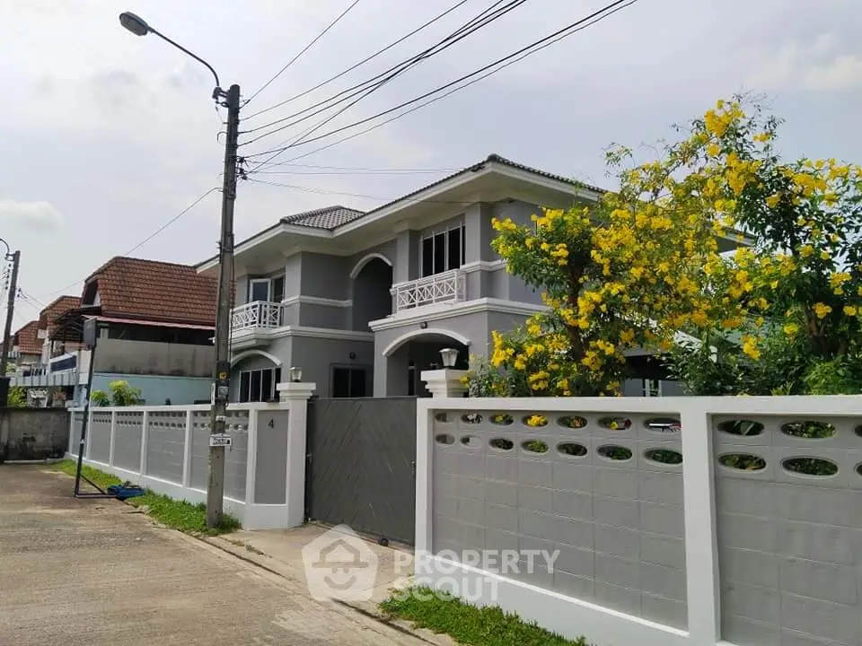 Charming two-story house with elegant balcony and lush garden in a serene neighborhood.
