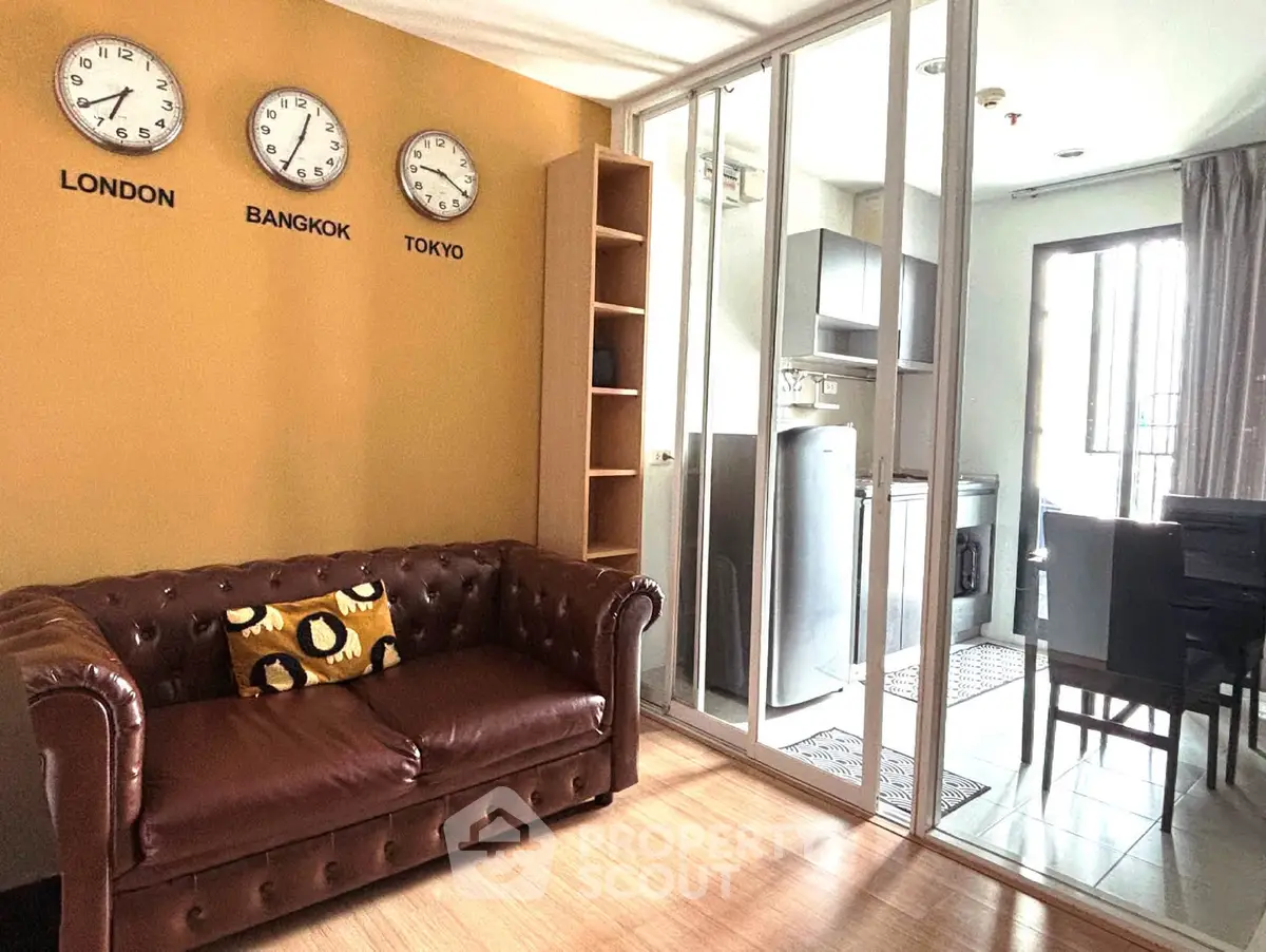 Stylish living room with leather sofa and world clocks, adjacent to modern kitchen.