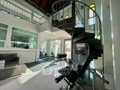 Modern gym with spiral staircase and fitness equipment in bright, spacious interior