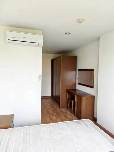Spacious bedroom with modern air conditioning and wooden furniture, perfect for comfort and style.