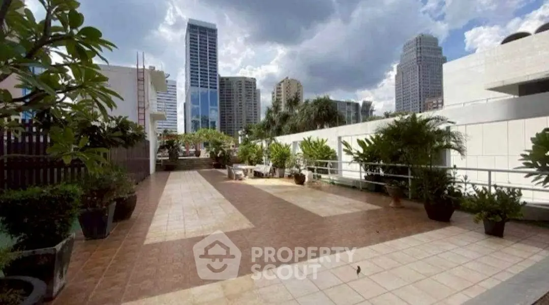 Spacious urban rooftop terrace with city skyline views and lush greenery.