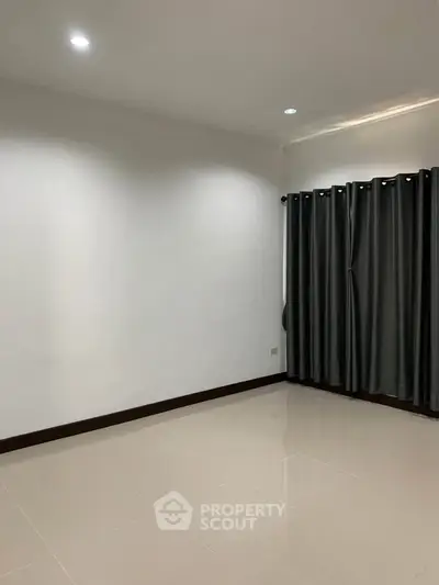 Spacious empty room with tiled floor and dark curtains, ideal for customization.