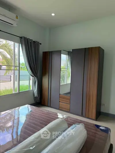Modern bedroom with large window and stylish wardrobe, offering a bright and inviting atmosphere.