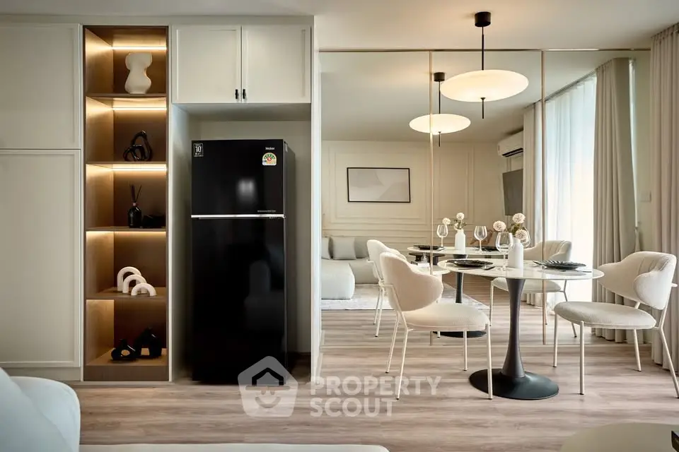 Stylish modern living room with dining area and sleek black fridge, elegant decor and lighting.