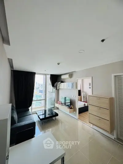 Modern living room with city view, sleek furniture, and natural light in a high-rise apartment.