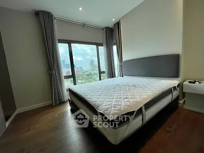 Spacious bedroom with large windows offering stunning city views and modern furnishings.