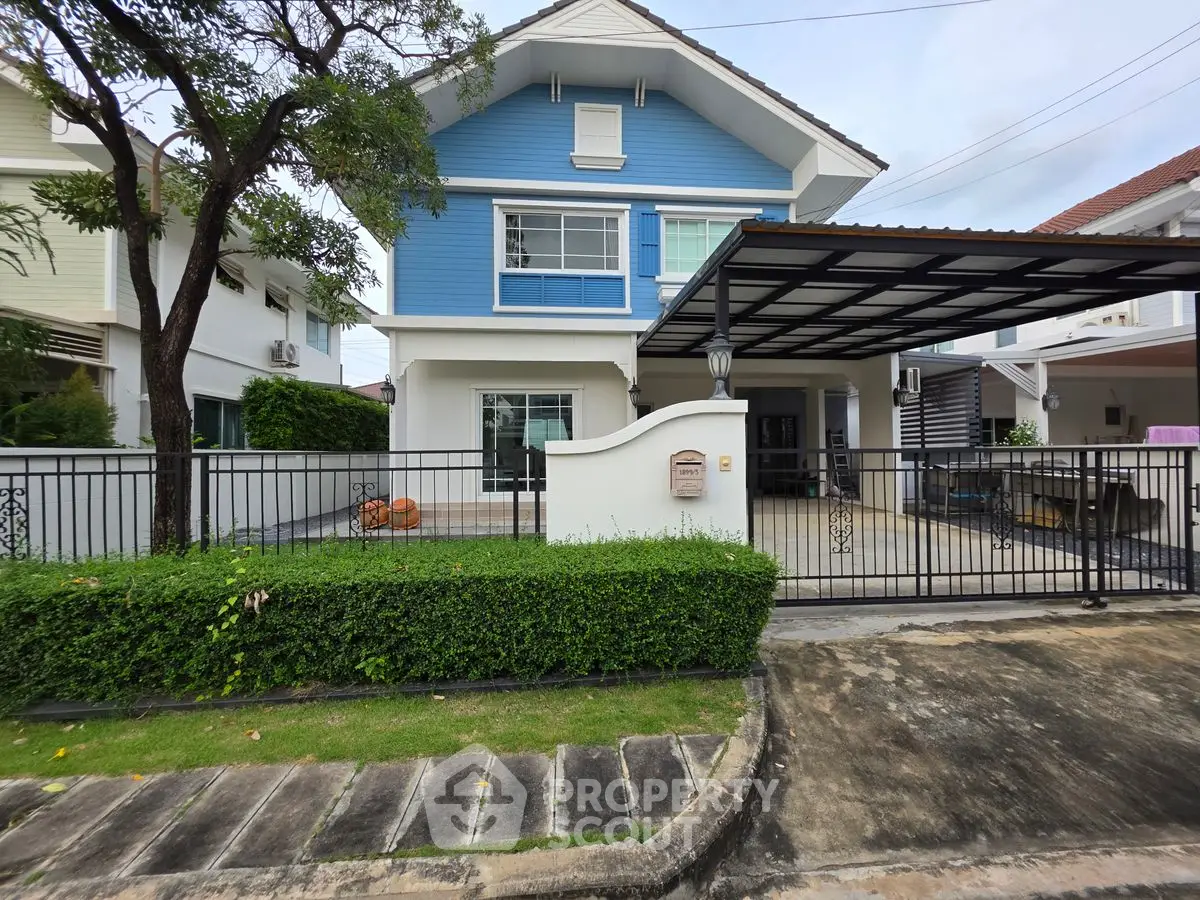 Charming two-story blue house with a spacious front yard and modern carport.