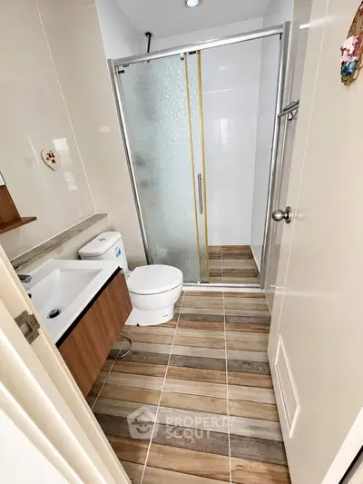 Modern bathroom with wooden accents and glass shower enclosure