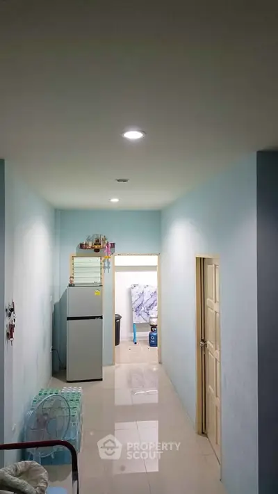 Compact hallway with refrigerator and minimal decor in a residential unit.