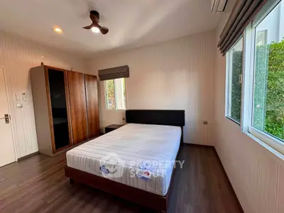 Spacious bedroom with large windows and modern furnishings in a serene setting.
