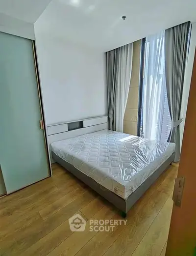 Modern bedroom with large windows and wooden flooring in a stylish apartment.