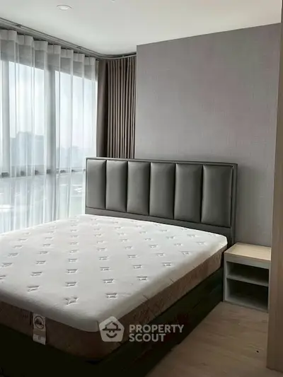 Modern bedroom with large window and stylish bed in a high-rise apartment.