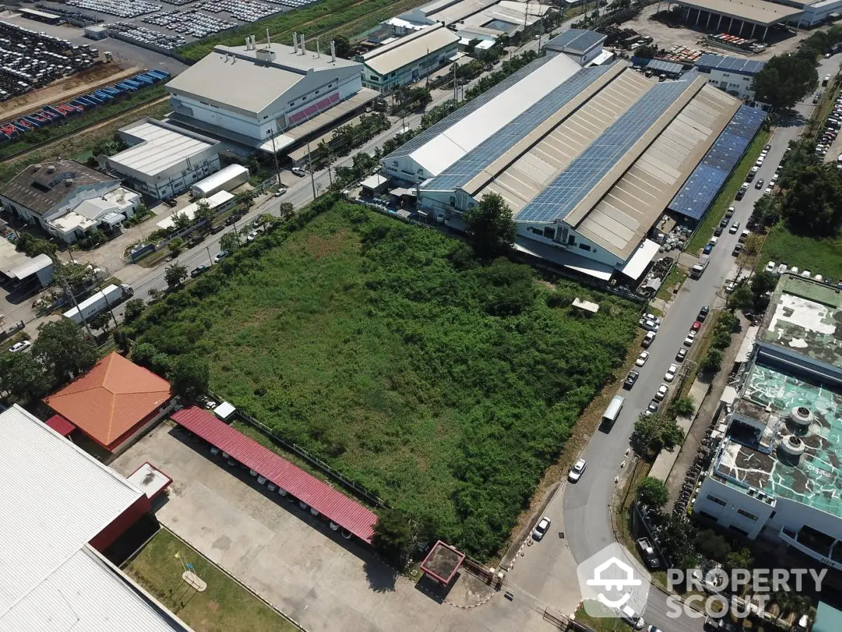 Aerial view of industrial area with large green plot and surrounding warehouses.