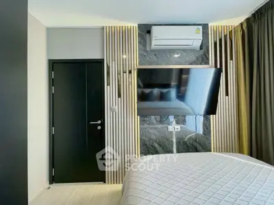 Modern bedroom with sleek design, featuring a wall-mounted TV and air conditioning unit.