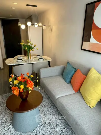 Modern living room with stylish decor and dining area, featuring vibrant cushions and floral arrangements.