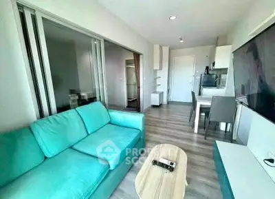 Modern living room with teal sofa and sleek kitchen in open layout apartment.