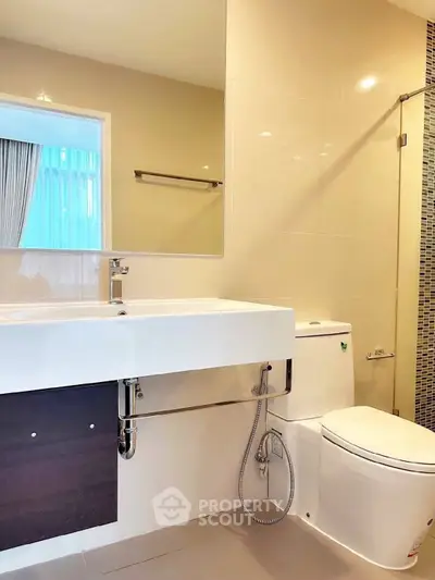 Modern bathroom with sleek fixtures and large mirror in a contemporary home.