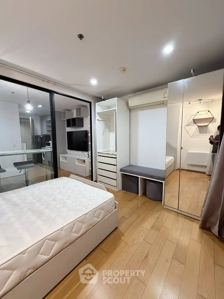 Modern bedroom with wooden flooring, mirrored wardrobe, and cozy ambiance
