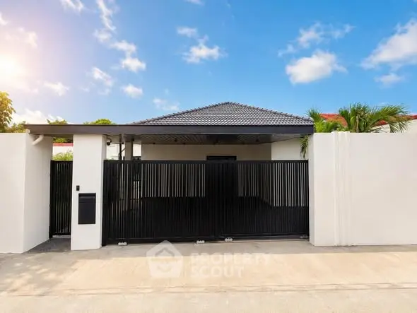 Modern single-story house with sleek black gate and minimalist design under a clear blue sky.