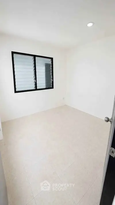 Spacious unfurnished room with tiled flooring and large window, perfect for customization.